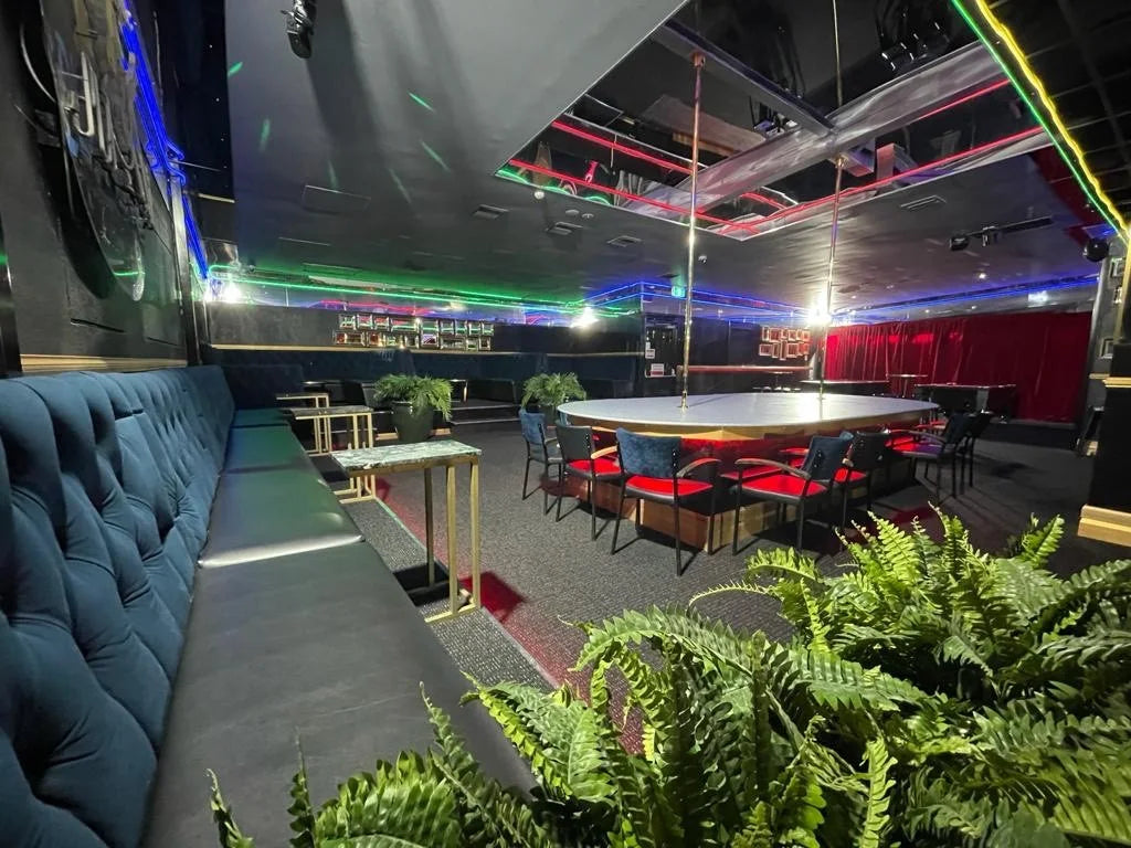Atmospheric hospitality lounge with blue banquette seating, circular table and lush ferns