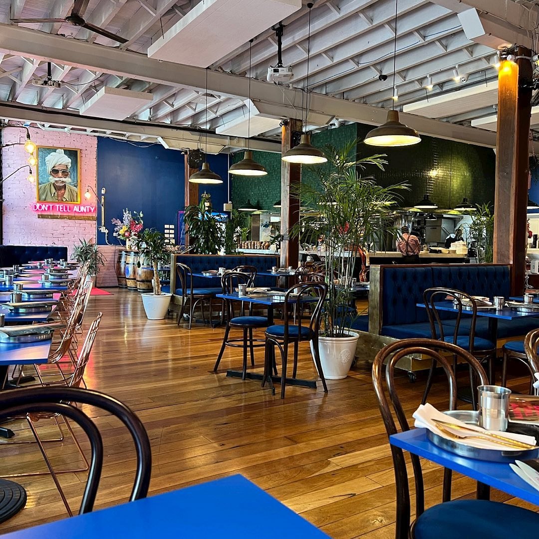Colourful hospitality dining room with blue banquettes, timber tables and pendant lighting
